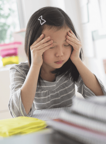 A young girl holding her head in pain